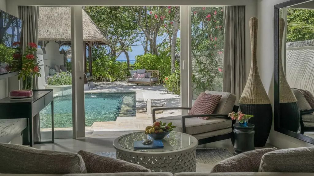 Heller Wohnbereich mit Blick auf privaten Pool und tropischen Garten