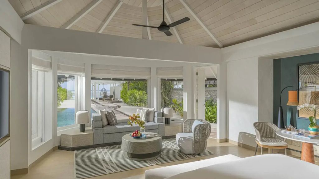 Geräumiges Wohnzimmer mit hellen Möbeln und Blick auf privaten Pool und Garten