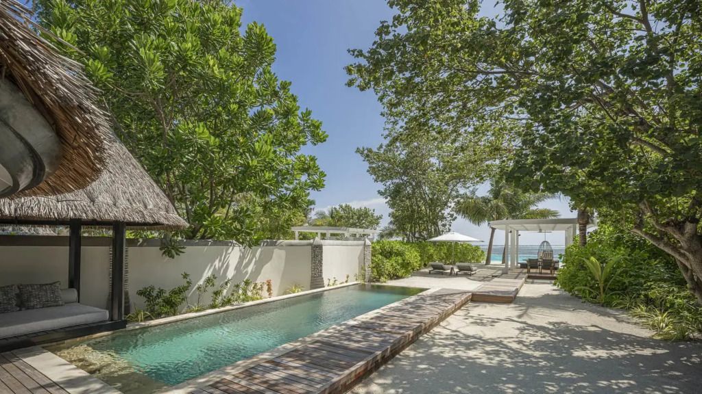 Privater Außenbereich mit Pool und Sonnenliegen umgeben von tropischer Vegetation