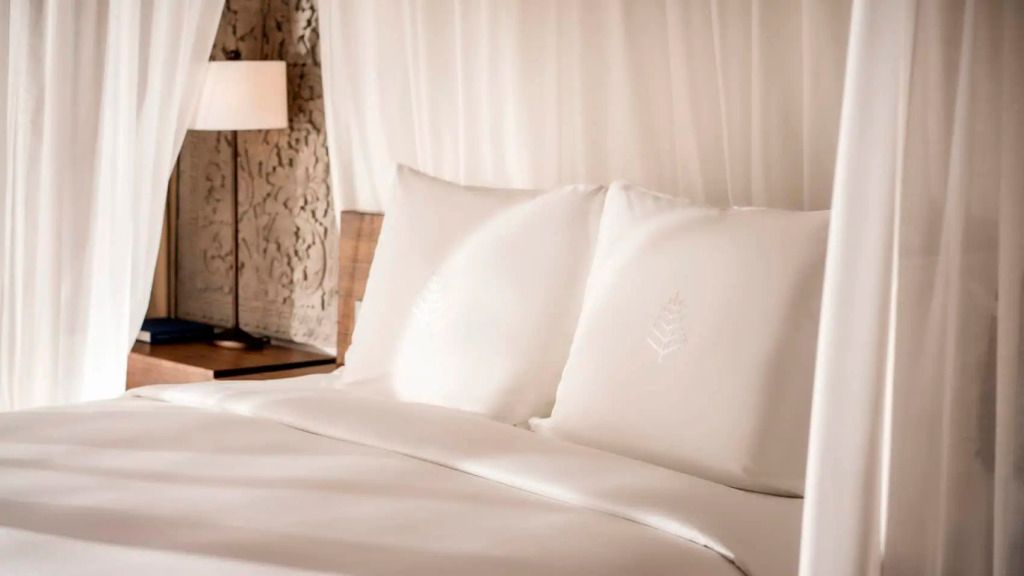 Elegantes Bett mit weißen Kissen und Nachttischlampe in einer luxuriösen Villa.