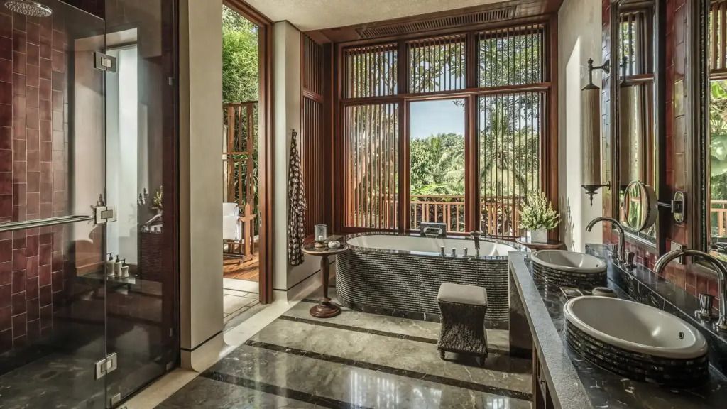 Badezimmer mit großer Fensterfront und Ausblick ins Grüne.