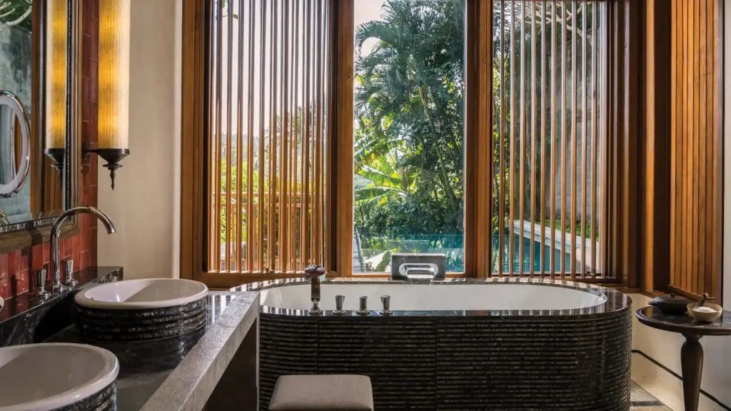 Exklusives Badezimmer mit freistehender Badewanne und Blick auf tropische Vegetation