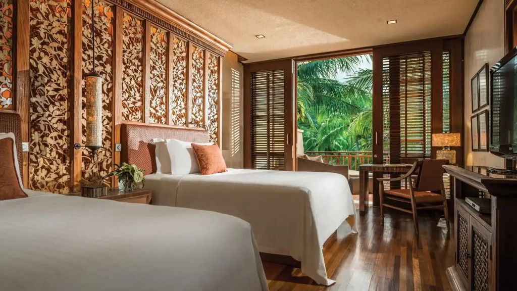 Schlafzimmer mit zwei Betten und Ausblick auf tropische Vegetation