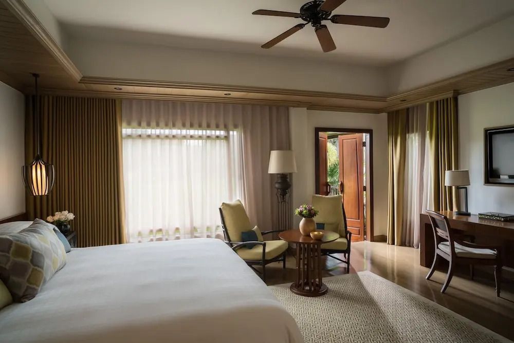 Helles Schlafzimmer mit gemütlicher Sitzecke und großem Fenster im Four Seasons Resort Chiang Mai