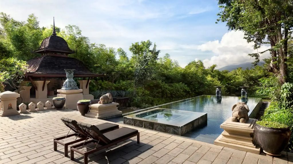 Infinity Pool mit Liegestühlen und Ausblick auf die umliegende Natur