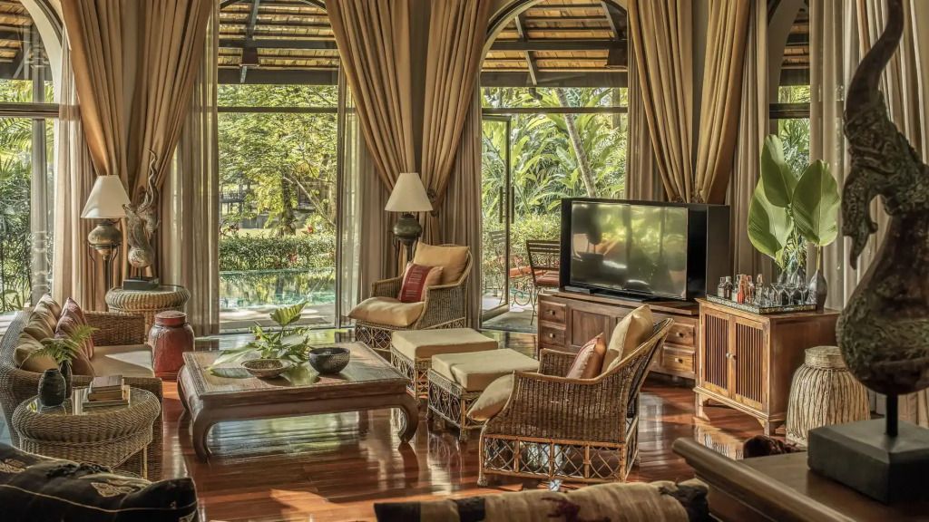 Geräumiges Wohnzimmer mit Rattanmöbeln und Blick auf den tropischen Garten