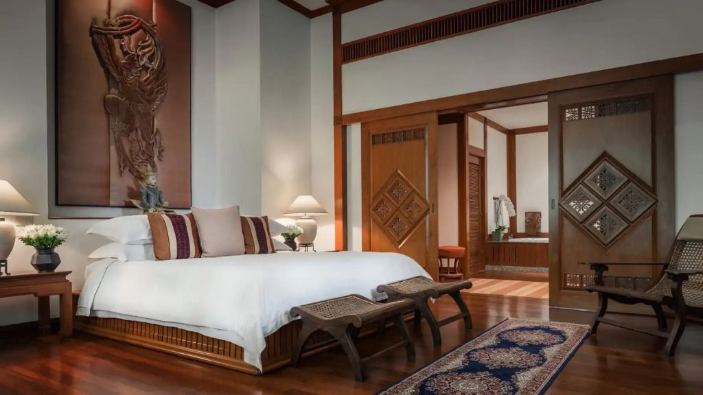Luxuriöses Schlafzimmer mit großem Bett und elegantem Holzmobiliar im Four Seasons Resort Chiang Mai.