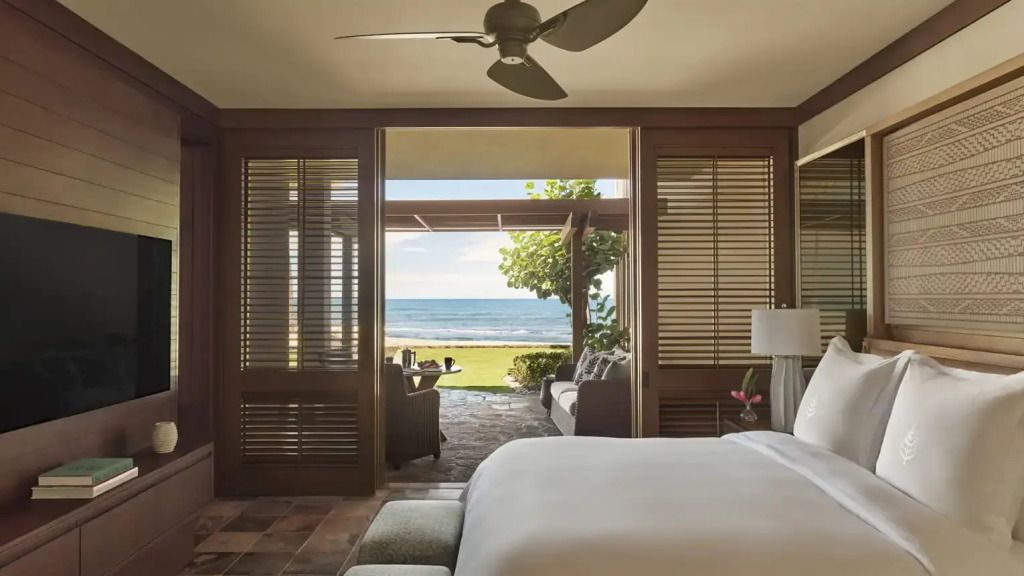 Geräumige Suite mit Blick auf das Meer durch große Fenstertüren und eleganten Holzmöbeln