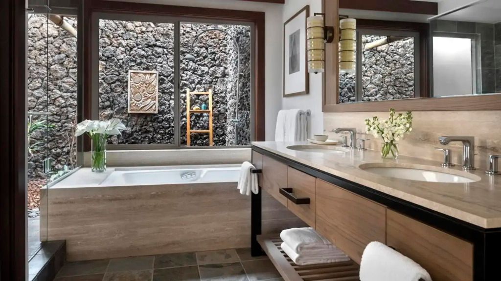 Luxuriöses Badezimmer mit freistehender Badewanne und Natursteinwand