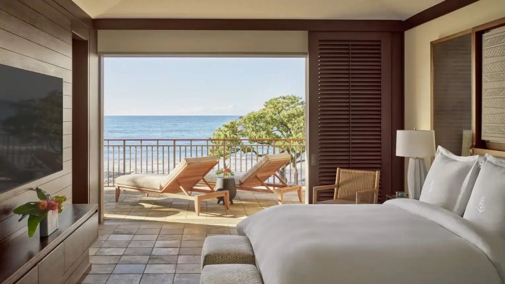 Suite mit Meerblick Terrasse, zwei Liegestühlen und sanftem Ozean im Hintergrund
