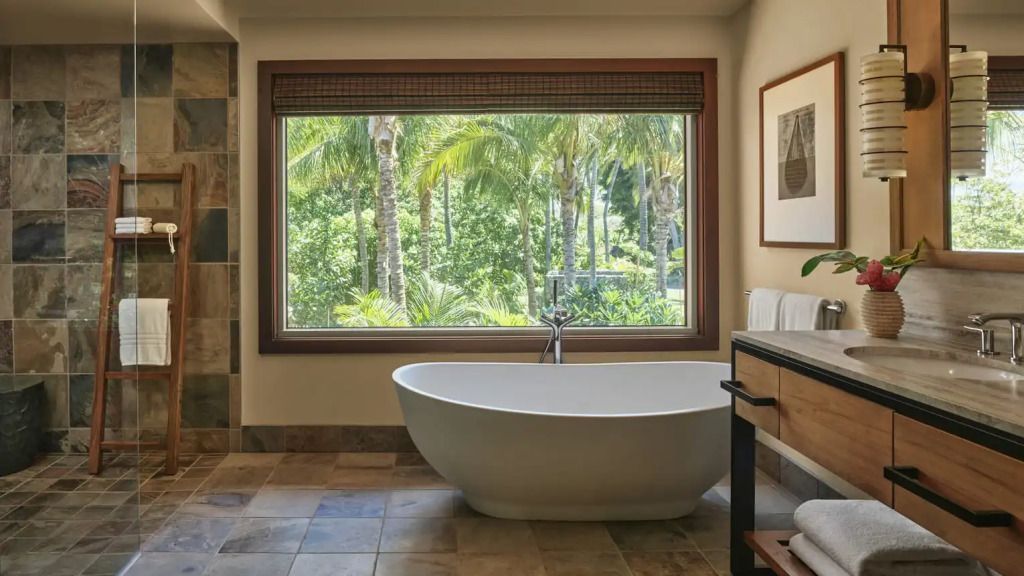 Luxuriöses Badezimmer mit freistehender Badewanne und Blick auf Palmen