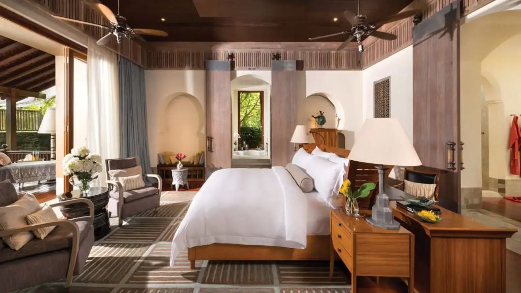 Luxuriöses Schlafzimmer mit Holzmöbeln und Blick auf den grünen Garten.