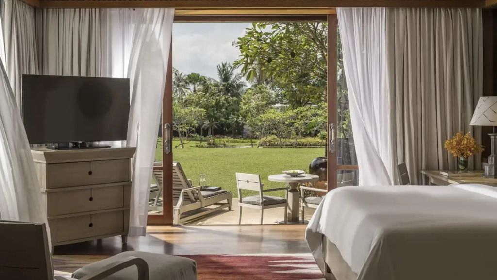 Panoramablick vom Zimmer auf eine private Terrasse und grünen Garten