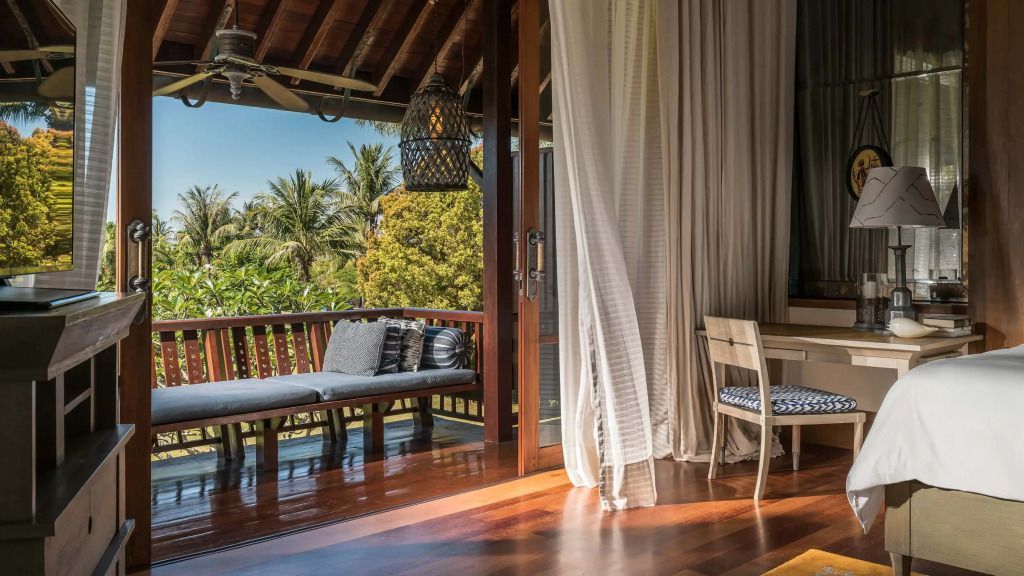 Balkon mit Sitzgelegenheiten und Aussicht auf tropische Pflanzen im Four Seasons Resort Langkawi.