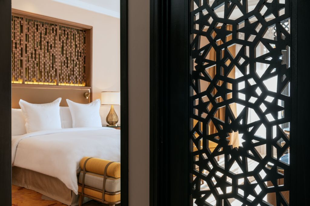 Elegantes Schlafzimmer der Villa mit kunstvoll geschnitztem Sichtschutz und luxuriösem Bett