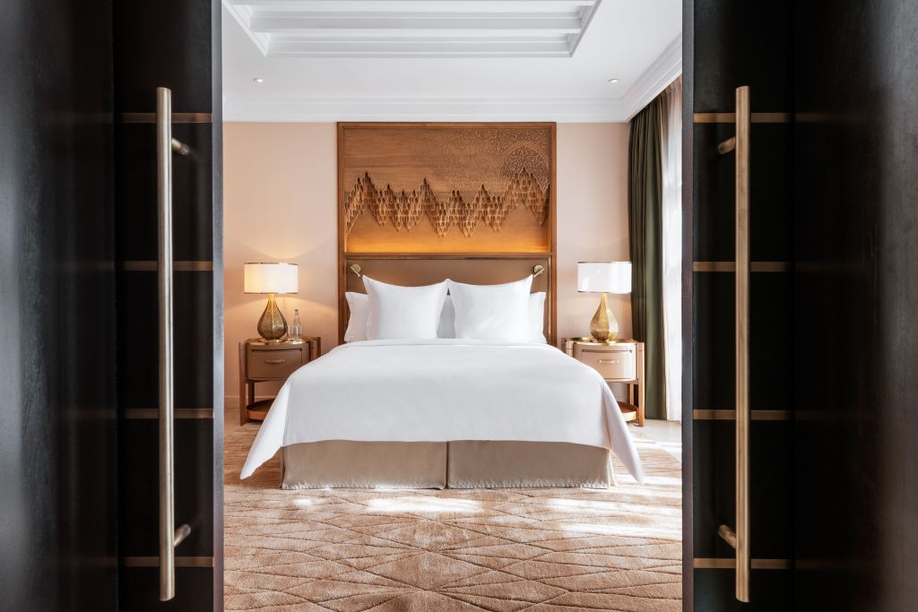Elegantes Schlafzimmer mit Kunst an der Wand und luxuriösem Teppichboden.
