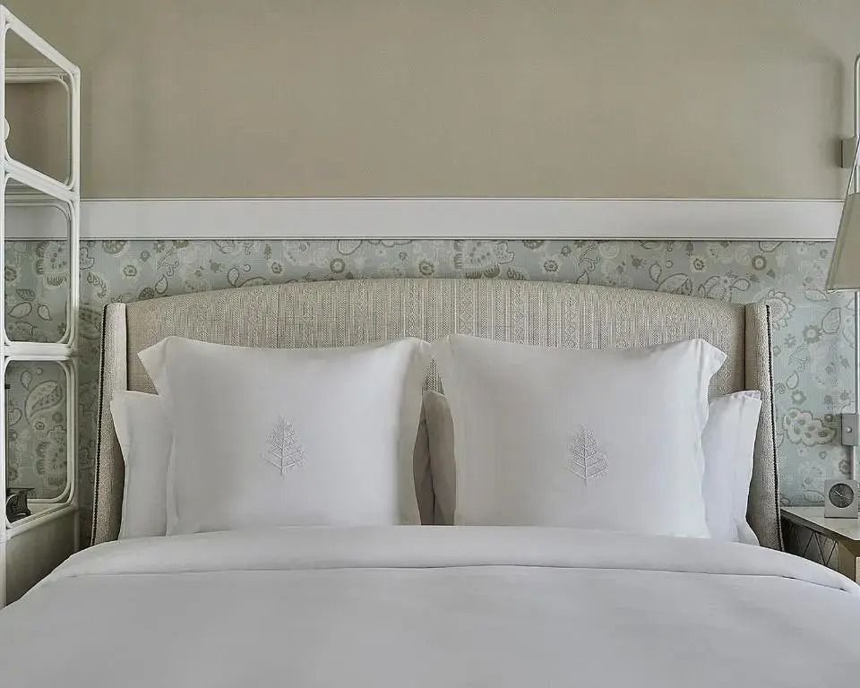 Elegantes Doppelbett mit weißen Kissen in einem stilvollen Resort-Zimmer