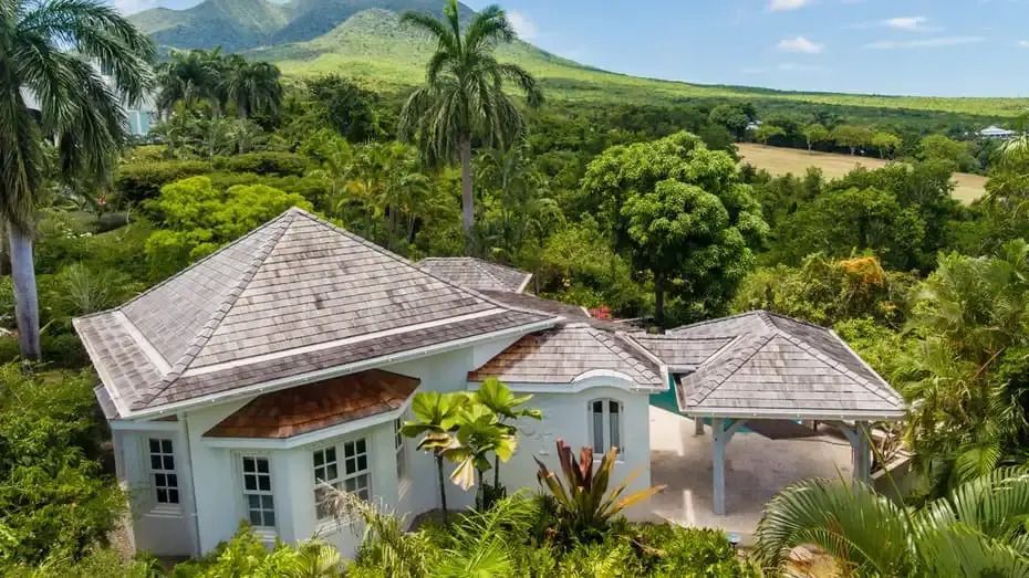Luftaufnahme einer Villa umgeben von üppiger Vegetation und Bergen