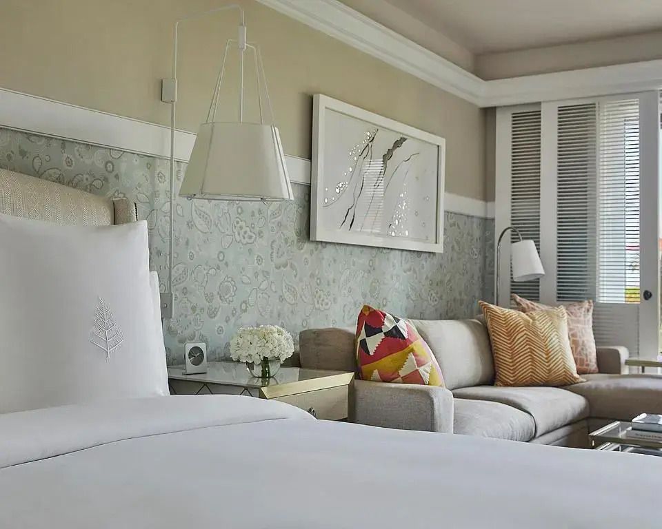 Gemütliches Bett im Ocean-Side Zimmer mit kunstvoller Wanddekoration.