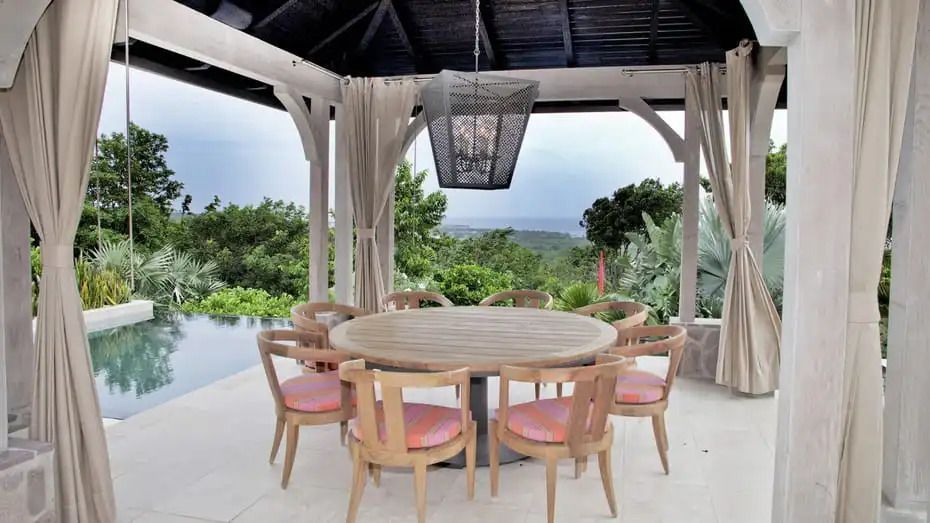 Essbereich im Freien mit runder Tischgruppe unter Dach mit Blick auf Natur im Four Seasons Resort Nevis.