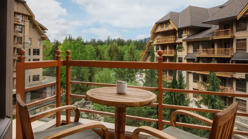 Balkon mit Sitzgelegenheit und Blick auf grüne Landschaft und Hotelarchitektur