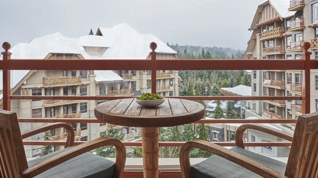 Balkon mit zwei Sesseln und Tisch, schneebedeckte Berge im Hintergrund
