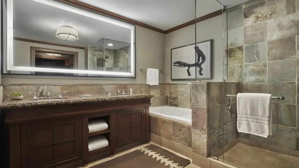 Modernes Badezimmer mit Steinfliesen und gut beleuchtetem Spiegel