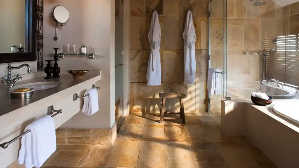 Elegantes Badezimmer mit Naturstein und Regendusche im Four Seasons Serengeti
