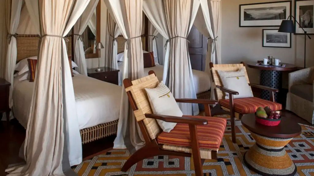 Doppelbettzimmer mit Sitzbereichen und Baldachinvorhängen im Four Seasons Serengeti