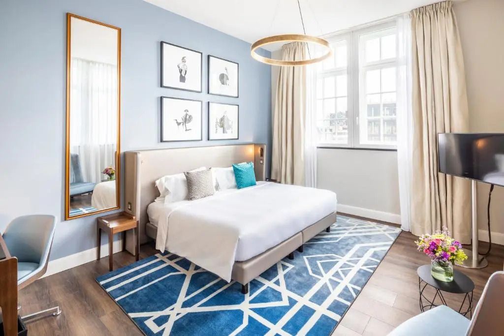 Modernes Schlafzimmer mit blauem Teppich und gemütlichem Bett in Fraser Suites Hamburg.