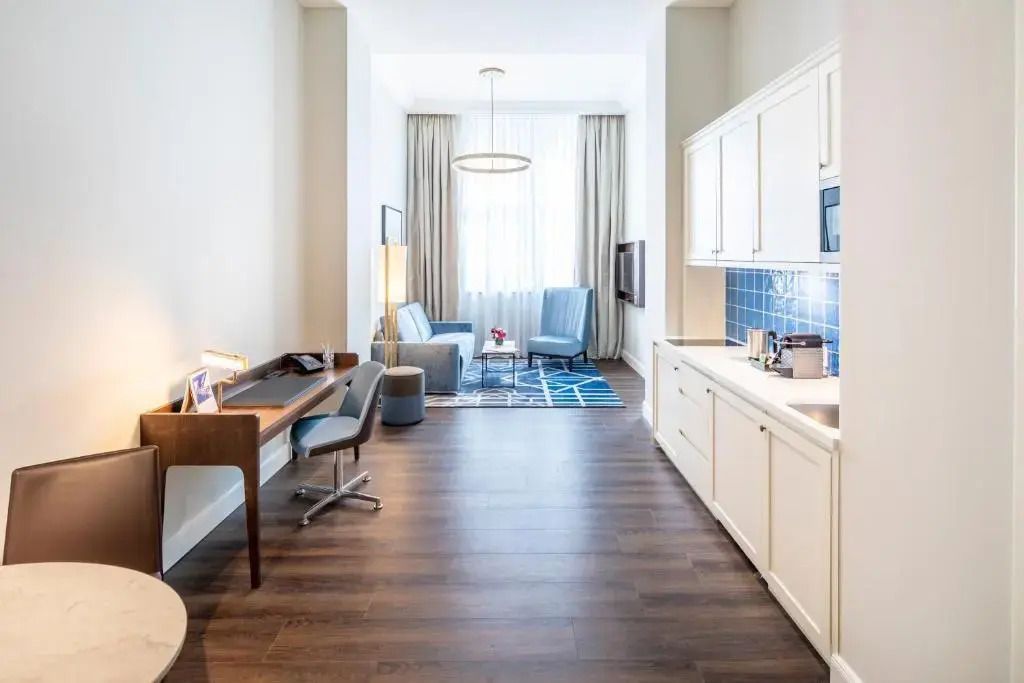 Geräumiges Zimmer mit Schreibtisch, Sitzbereich und Küchenzeile in modernem Design