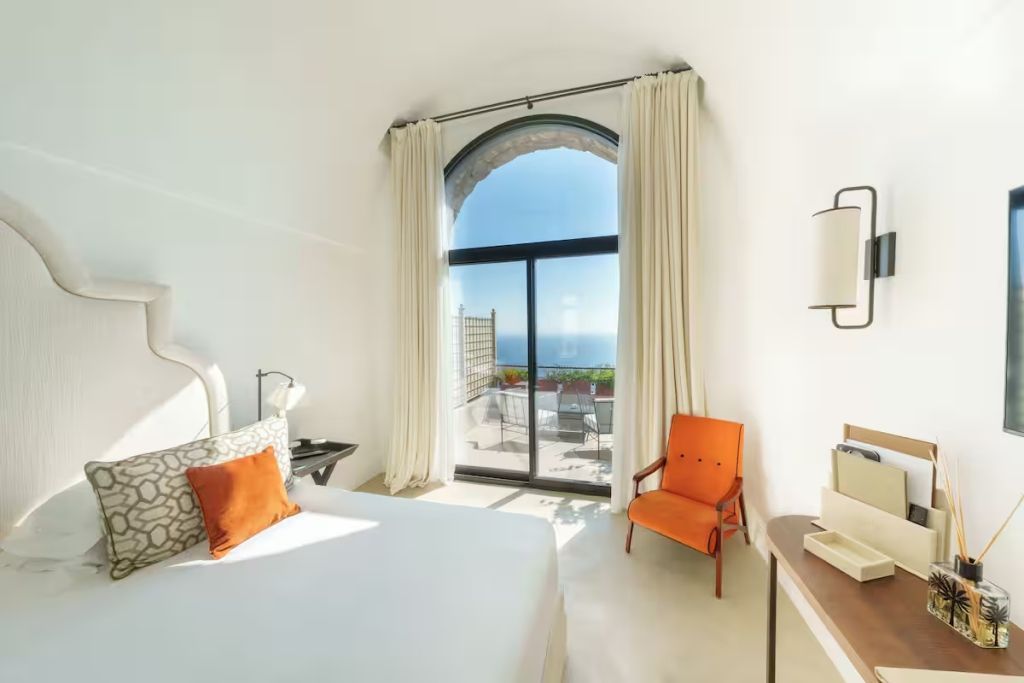 Zimmer mit Doppelbett und Panoramafenster mit Meerblick.