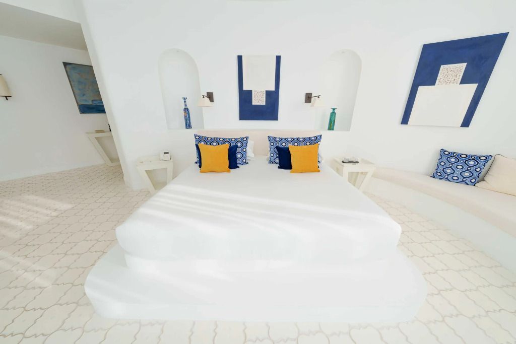 Elegantes Zimmer mit weißen Wänden und kontrastreichen Kissen im Furore Grand Hotel