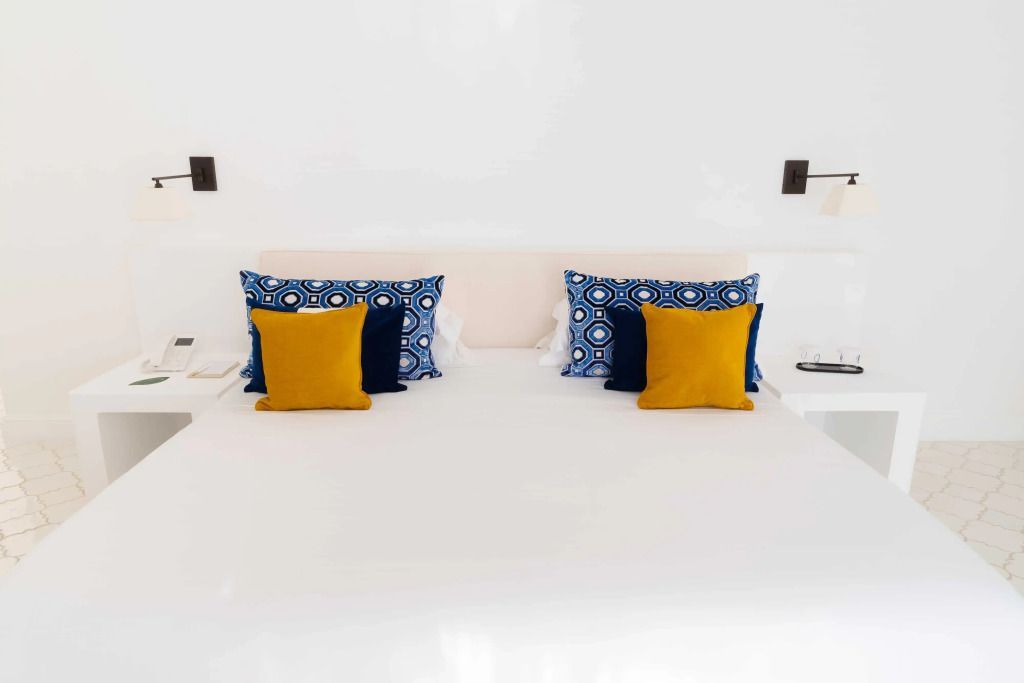 Weißes Bett mit bunten Kissen in der Furore Corner Suite im Furore Grand Hotel