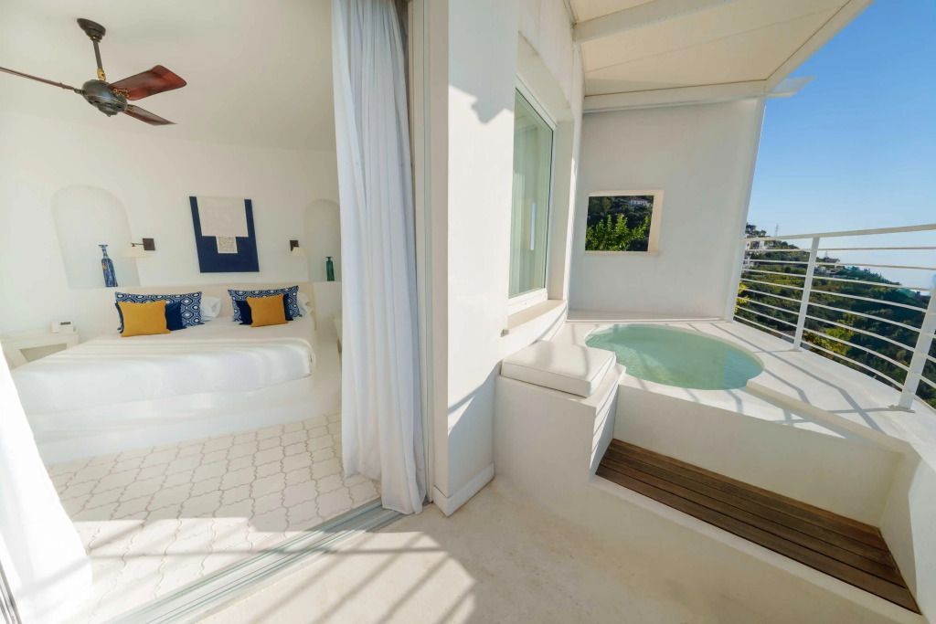 Helles Zimmer mit Zugang zu einer Terrasse mit Whirlpool im Furore Grand Hotel