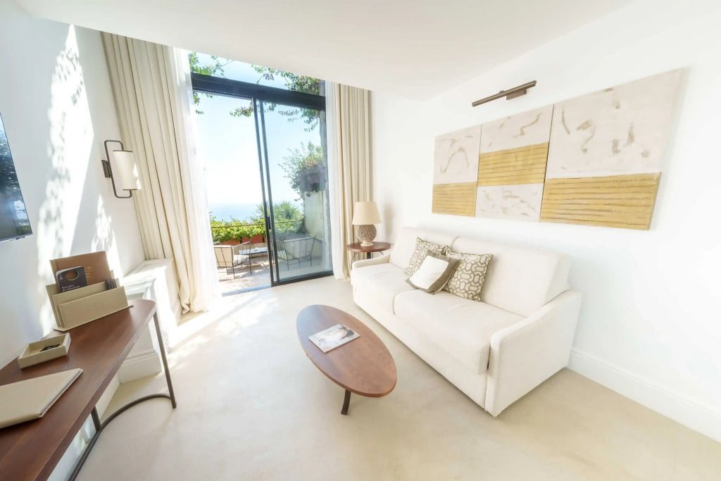 Lichtdurchflutetes Wohnzimmer mit Sofa und Zugang zur Terrasse mit Meerblick