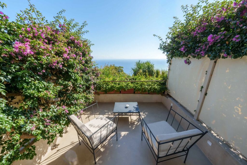 Terrasse mit Sitzgelegenheiten und üppiger Bepflanzung mit Meerblick