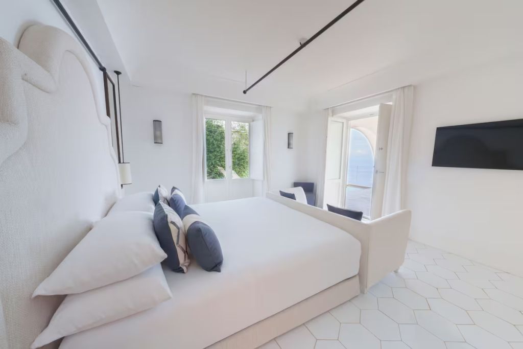 Geräumiges Schlafzimmer mit weißer Einrichtung und Meerblick