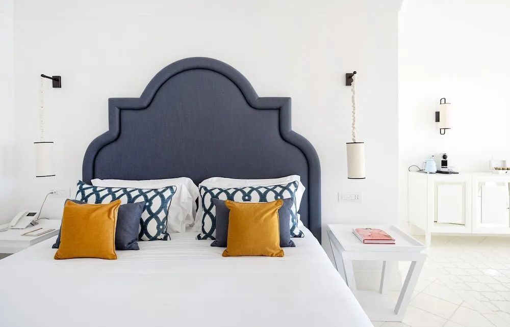Luxuriöses Bett mit blauer Kopflehne und dekorativen Kissen in der Luxus Suite