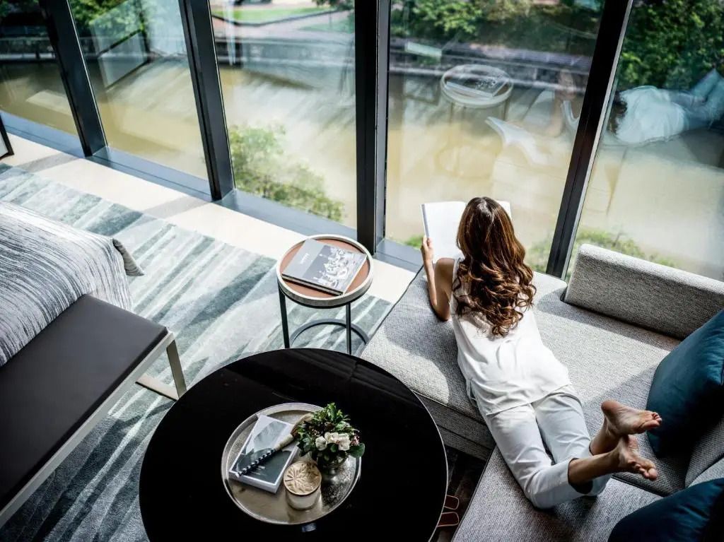 Person liegt in moderner Suite und liest mit Blick auf den Fluss