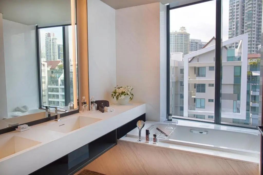Elegante Badewanne in einer Suite mit Blick auf die Stadt durch große Fenster