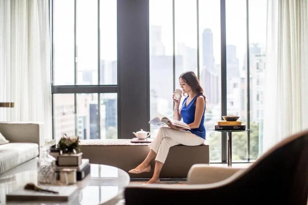 Frau in modernem Penthouse mit Panoramafenster und Stadtblick