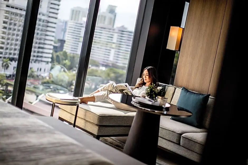 Frau entspannt sich mit Buch in moderner Suite mit Aussicht