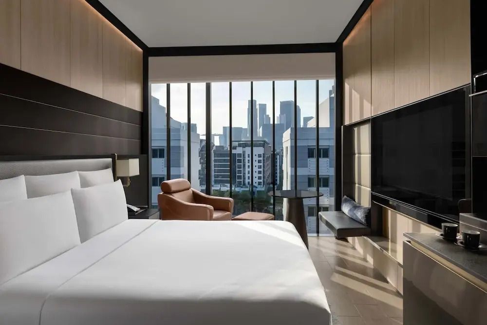 Modernes Hotelzimmer mit Doppelbett und großer Fensterfront mit Stadtblick