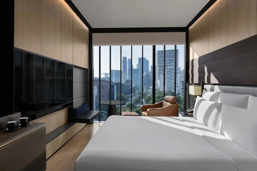 Hell eingerichtetes Hotelzimmer mit Doppelbett und Panorama-Fenstern