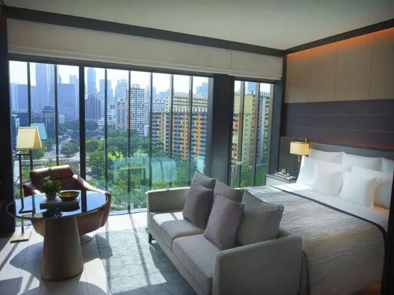 Helles Studio mit Doppelbett, Sofaecke und Panoramafenstern mit Stadtblick
