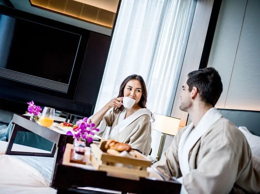 Paar im Bademantel genießt Frühstück im Hotelzimmer
