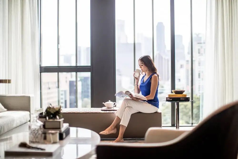 Geräumige Suite mit großer Fensterfront und Blick auf die Skyline von Singapur