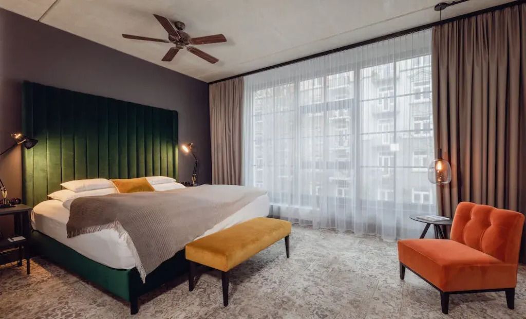 Elegantes Doppelzimmer mit grünem Kopfteil und großem Fenster