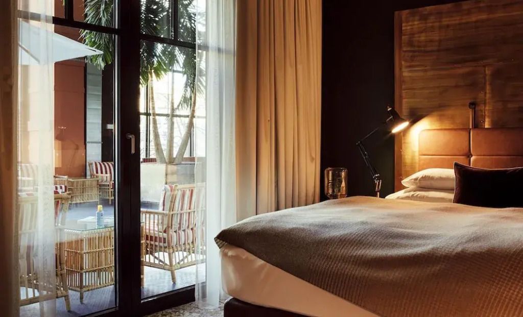 Sonnendurchflutetes Zimmer mit Blick auf eine Terrasse und Vorhänge im Gastwerk Hotel Hamburg.